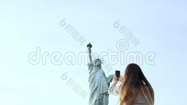 美丽微笑的欧洲旅游妇女在纽约市拍摄自由女神像的智能手机照片