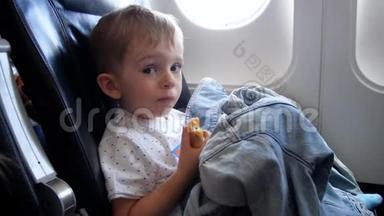 在飞机上长<strong>时</strong>间<strong>飞行时</strong>，疲惫困倦的小男孩在吃包子