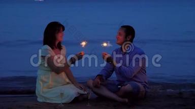 浪漫<strong>情侣</strong>在日落时分在海滩上用烟<strong>花</strong>和香槟庆祝