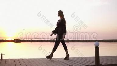 慢动作，从<strong>木墩</strong>旁走着的美丽的长发黑衣女子的侧面拍摄的。 清晨黄昏