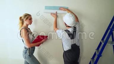 施工现场的年轻一对工人在<strong>墙上贴</strong>墙纸