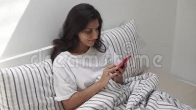 学生女孩早上坐在床上用手机发信息