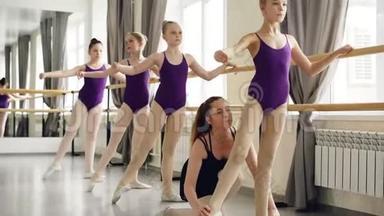芭蕾舞老师正在帮助她的小女学生在舞蹈学校上课时手臂、手和腿的位置