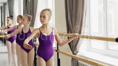 年轻的<strong>芭蕾舞</strong>演员穿着时髦的<strong>芭蕾舞</strong>服，在轻舞厅练习手臂<strong>动作</strong>，用木制木制芭蕾表演。