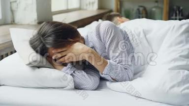 伤心的女人是睡衣躺在床上，和躺在她身边背对着她的丈夫打架后哭泣