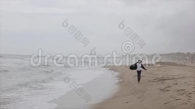 一个穿暖和衣服的漂亮女孩沿着海滨跑。 刮风的一天，海面上波涛汹涌