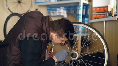 年轻的维修工正在擦洗自行车车轮上的污垢，用一块布料清洗，然后用