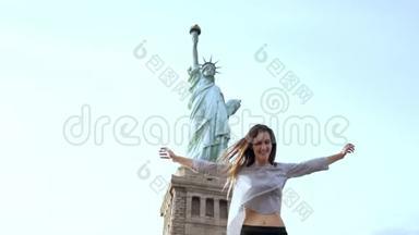 快乐兴奋微笑的欧洲旅游妇女在纽约自由女神像举起手臂在夏季的一天慢动作。
