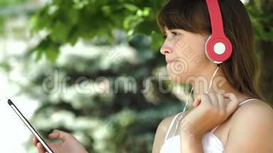 戴着耳机听音乐的小女孩在平板电脑上走来走去。 特写