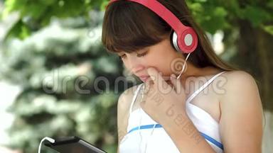 戴着耳机听音乐的小女孩在平板电脑上走来走去。 特写