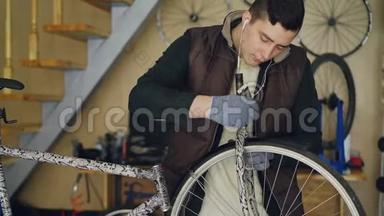 集中精力的年轻机械师在修理自行车时用耳机润滑自行车车轮和听音乐