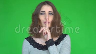 安静，求你了！ 年轻女子用食指举在嘴唇上的肖像，显示安静的标志