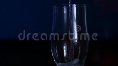 特写香槟在<strong>电视背景</strong>下流入玻璃杯。 慢动作