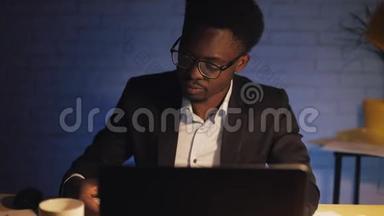 年轻的黑人商人带着笔记本电脑和文件在夜间办公室工作。 他在文件上签字。 <strong>商务</strong>
