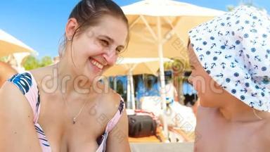 4k视频快乐微笑男孩涂防晒霜紫外线乳霜在沙滩妈妈脸上