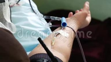 献血时，女人躺在沙发上挤着胳膊。 捐献输血