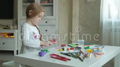 一个小女孩玩橡皮泥，用手把它<strong>卷起</strong>来，在上面剪一个图形、图形和彩色铅笔
