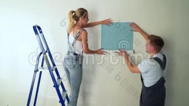 施工现场的年轻一对工人在墙上贴墙纸