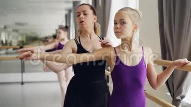 有经验的芭蕾舞老师正在教年轻的女学生芭蕾动作和姿势，而勤奋的女孩则是如此