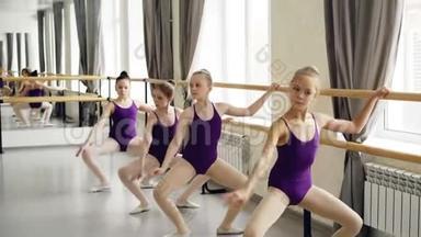 小女孩开始跳芭蕾，跳跳舞的舞女们正在做练习，拿着芭蕾舞棒练习不同的姿势