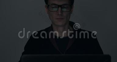 深夜在黑暗房间里用笔记本电脑工作的男人的肖像