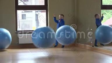 快乐的小孩在健身房玩大球，很多球不打灵活的男孩