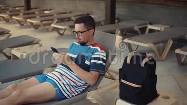 男人躺在躺椅上，拿着智能手机。
