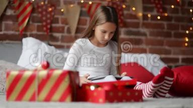 圣诞快乐的小女孩帕贾玛用圣诞老人送给她的<strong>数码</strong>平板电脑坐在卧室里，装饰着<strong>家</strong>
