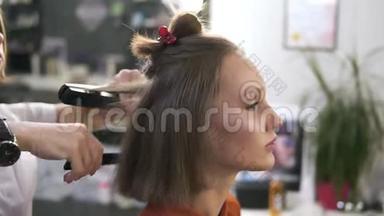 一个美丽的年轻女子在美容院随意化妆的侧视镜头。 专业的理发师给她做造型