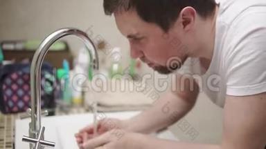 一位成年男子早上正在浴室的水槽上方<strong>洗脸</strong>，特写镜头