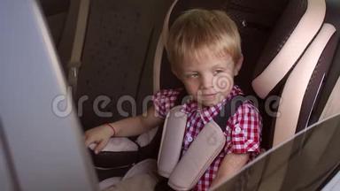 一个快乐的小男孩坐在棕色的<strong>儿童汽车</strong>座椅上，竖起大拇指。