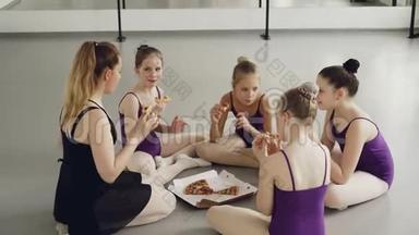 快乐的孩子们，芭蕾舞学生和他们的老师在舞蹈课之间的午休时间吃披萨。 女孩
