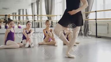 芭蕾舞教师专业芭蕾舞演员踮起脚尖向她的小学生展示动作