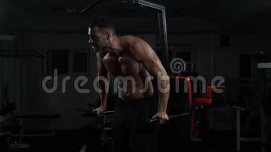 肌肉男在交叉健身馆的<strong>高低</strong>杠上做俯卧撑。