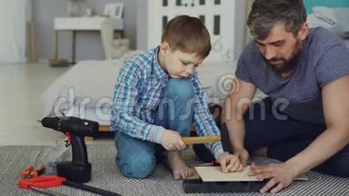 长胡子的父亲和年轻可爱的儿子在家里用木床单做鸟舍。 儿童和父母的概念