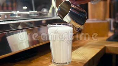 咖啡师正<strong>在</strong>将咖啡倒入一杯加牛奶的<strong>玻璃杯中</strong>，制作一个拉丁或纯白咖啡