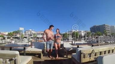 浪漫的旅行，快乐的男人和女朋友穿着泳衣，手牵着手在暑假的码头上跑步