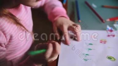 镜头滑过可爱的白种人小女孩，在一张桌子特写上用不同颜色的铅笔在纸上画画。