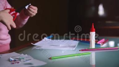 镜头滑落在穿着粉色毛衣的<strong>小</strong>女孩的手上，她在桌子上用各种<strong>文具</strong>剪出纸的形状。