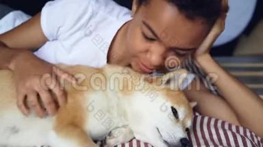 特写镜头爱狗主人抚摸可爱的宠物躺在床上，女孩抚摸着动物，抓着它