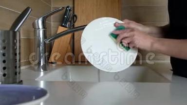 女人的手在<strong>厨房</strong>水槽里<strong>冲洗</strong>盘子-在家里做家务。 洗碗常规，静态摄像头.. 快关门。