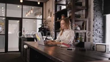 一个漂亮的金发女孩穿着一件白色的商业衬衫，打开一台笔记本电脑开始工作的肖像。 一个年轻人