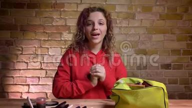 年轻美女博主的特写肖像，在镜头前录制关于在布里克肯墙上使用化妆品的视频