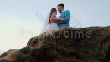 美丽的年轻<strong>新婚</strong>夫妇站在海边，岩石。 <strong>新婚</strong>夫妇在一起：拥抱、亲吻和关怀