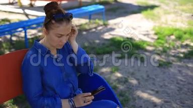 夏天，公园里坐在一张长凳上，一个年轻漂亮的女人穿着<strong>牛仔裙</strong>，脸上长着雀斑