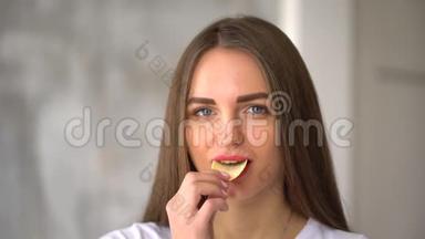 女孩在街上在户外吃<strong>薯片</strong>。 漂亮的年轻女人吃<strong>薯片</strong>。