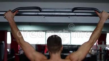 在健身房，一个男人用肌肉发达的手臂做秋千