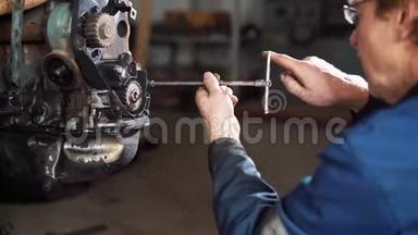 一个工人在<strong>维修中心</strong>修理一辆坏汽车的发动机。