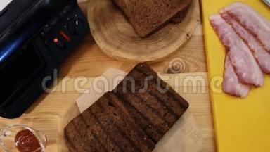 在厨房里做三明治。 制作三明治的布景的顶部视图。 烤面包，培根，酱汁，木制三明治