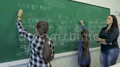 小学。 小女生在教室的绿色黑板上写数字